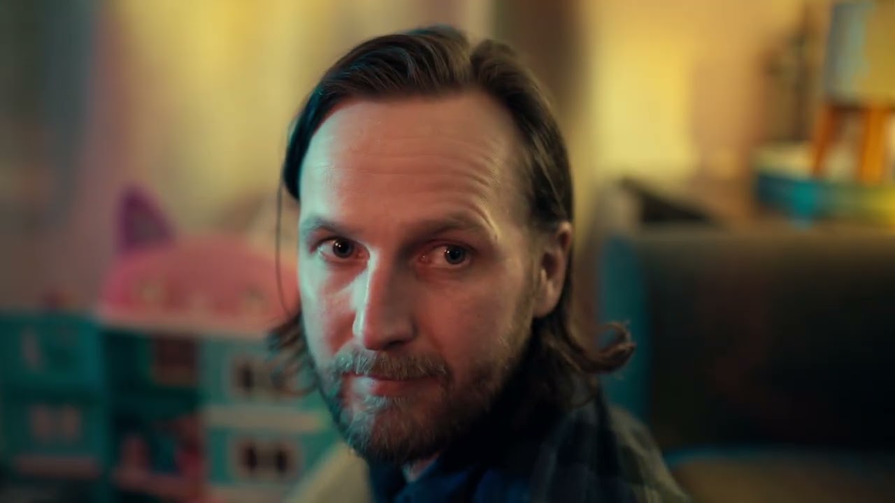 Steve Allgood looking into the lens in a warmly lit living room, from the TheraPsil public service announcement.